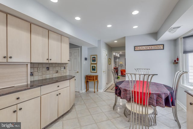 kitchen featuring dark stone countertops, cream cabinets, and tasteful backsplash