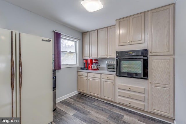 kitchen featuring black oven, light hardwood / wood-style flooring, and white fridge