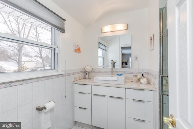 bathroom featuring tile walls, vaulted ceiling, and vanity