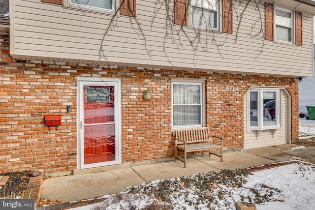 snow covered property entrance with a patio