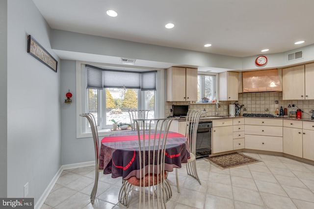 kitchen featuring light brown cabinetry, dishwasher, custom exhaust hood, backsplash, and stainless steel gas cooktop