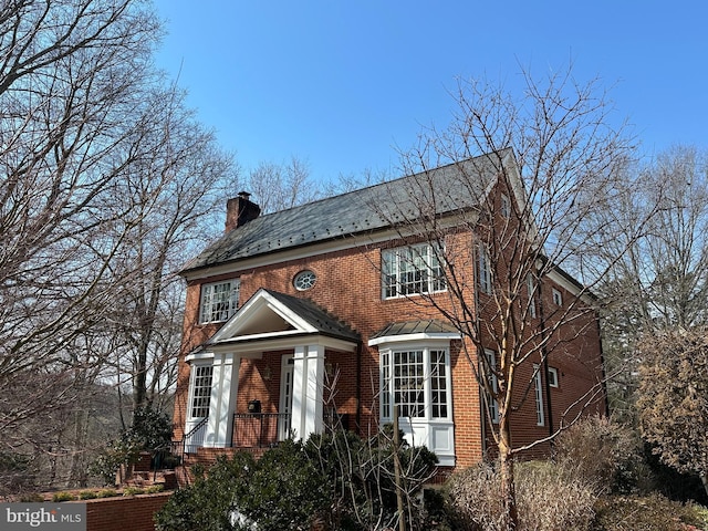 georgian-style home featuring brick siding and a chimney