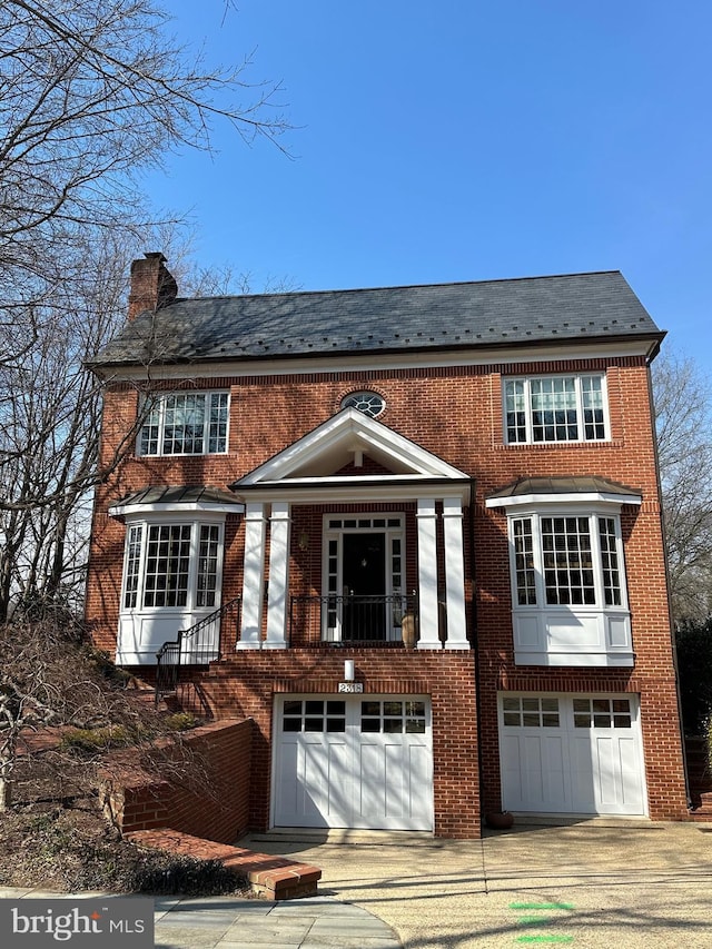 view of front of home featuring a high end roof, brick siding, a chimney, and an attached garage