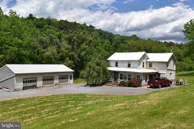 view of front of house with a garage, a front yard, an outdoor structure, and a porch