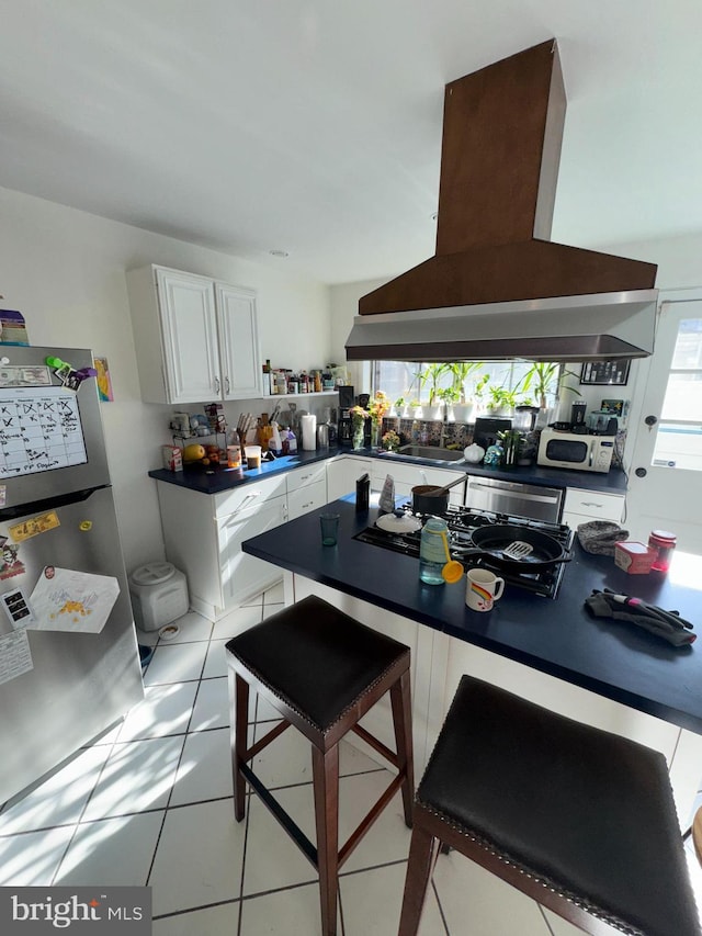 kitchen featuring stainless steel fridge, plenty of natural light, island range hood, and white cabinetry