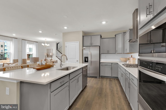 kitchen featuring stainless steel appliances, gray cabinetry, a kitchen island with sink, and sink