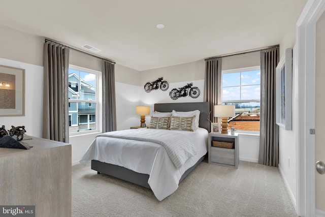 bedroom with light colored carpet and multiple windows