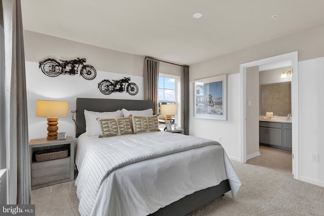 bedroom featuring ensuite bath, light colored carpet, and sink