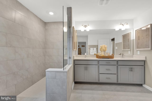 bathroom featuring tile patterned floors, vanity, and a tile shower