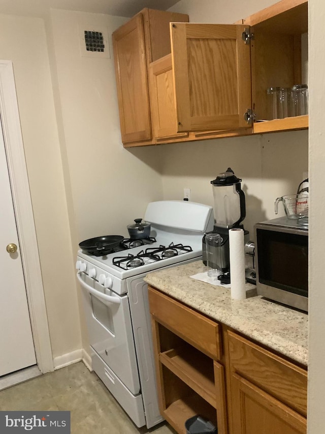 kitchen with light stone countertops and gas range gas stove