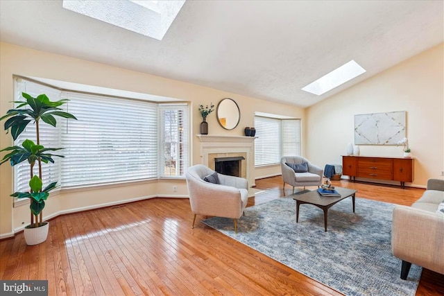 living room with lofted ceiling with skylight and light hardwood / wood-style floors