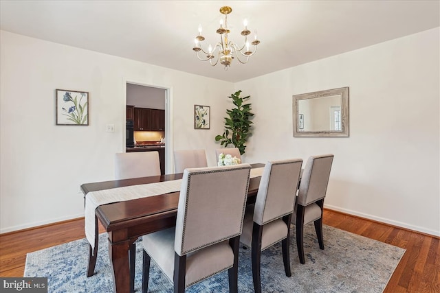 dining room with dark wood-type flooring and a chandelier