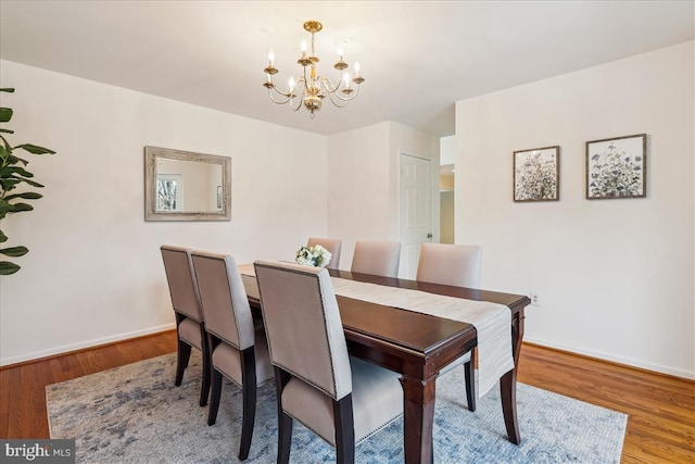 dining room featuring wood-type flooring and an inviting chandelier