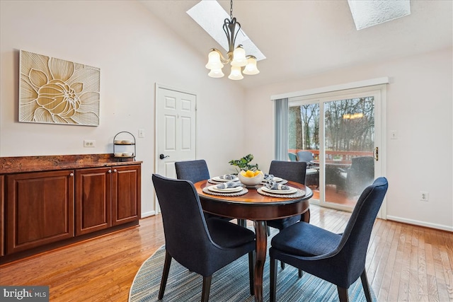 dining area with high vaulted ceiling, light wood-type flooring, and an inviting chandelier