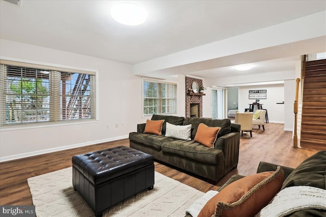 living room featuring wood-type flooring and a brick fireplace