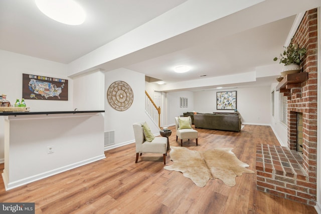 living area with hardwood / wood-style floors and a brick fireplace