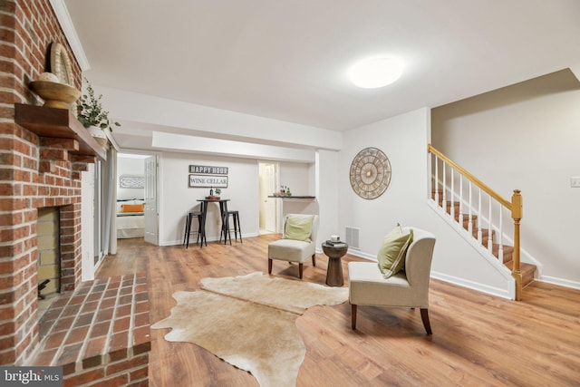 living area featuring hardwood / wood-style flooring and a brick fireplace