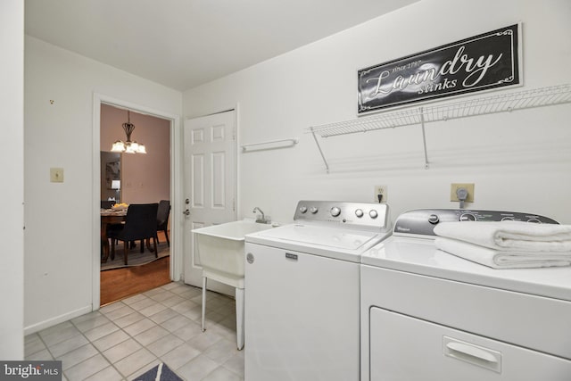 laundry area with sink, washing machine and dryer, a chandelier, and light tile patterned flooring