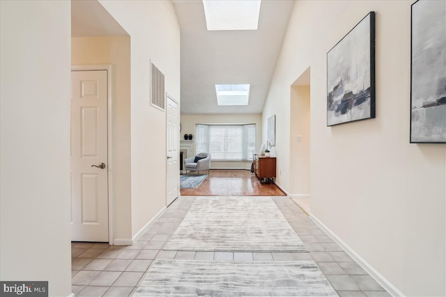 corridor featuring light tile patterned flooring and a skylight