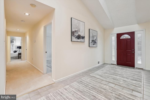 entryway with vaulted ceiling and light colored carpet