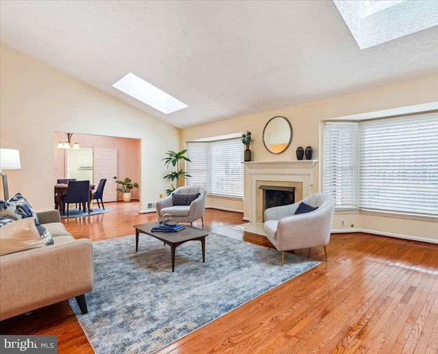 living room featuring wood-type flooring, high vaulted ceiling, and a skylight