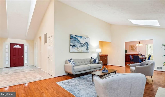 living room with a skylight, wood-type flooring, and high vaulted ceiling