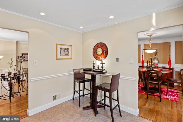 dining space with crown molding and light wood-type flooring