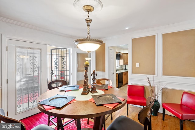 dining area with crown molding, sink, and light wood-type flooring