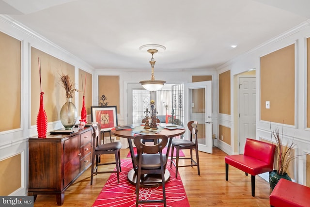 dining space featuring ornamental molding and light hardwood / wood-style floors