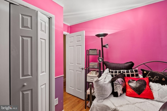 bedroom with ornamental molding and light hardwood / wood-style floors