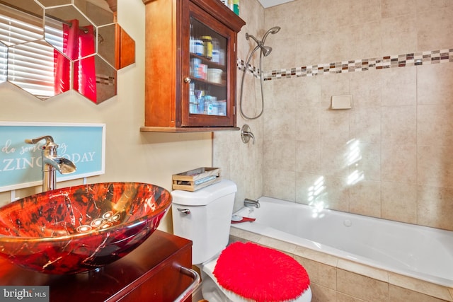 full bathroom featuring sink, tiled shower / bath combo, and toilet