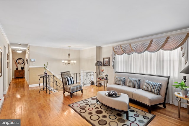 living room featuring ornamental molding, a chandelier, and light hardwood / wood-style floors