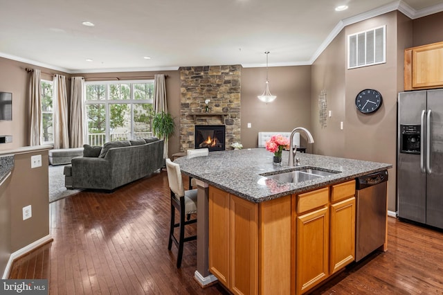 kitchen featuring stone counters, appliances with stainless steel finishes, sink, a kitchen island with sink, and crown molding