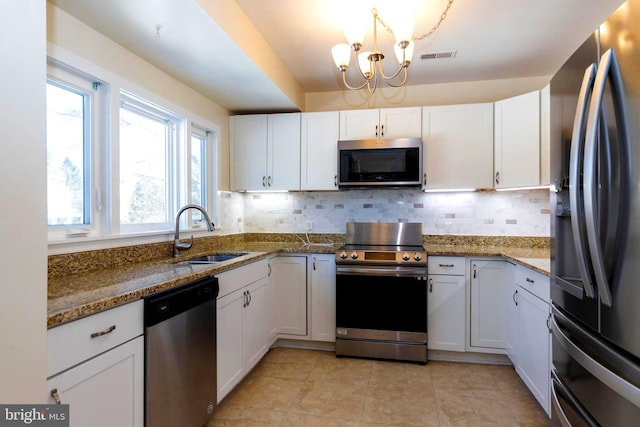 kitchen featuring sink, dark stone countertops, stainless steel appliances, decorative backsplash, and white cabinets