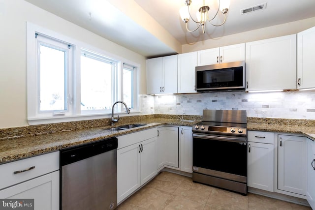 kitchen with stainless steel appliances, sink, dark stone counters, and white cabinets