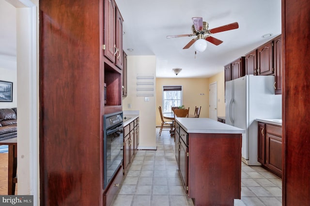 kitchen with ceiling fan, a kitchen island, black oven, and white fridge