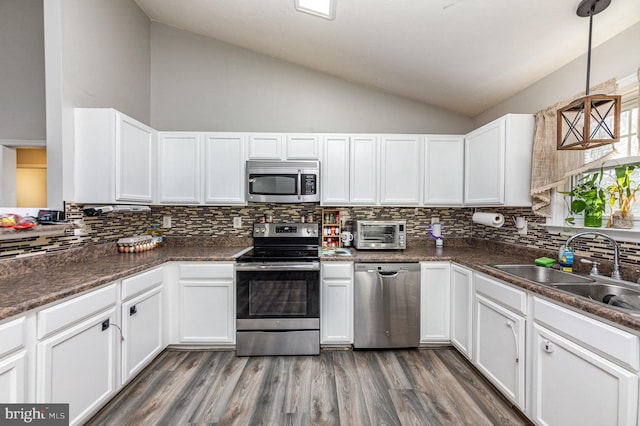 kitchen with lofted ceiling, sink, white cabinetry, decorative light fixtures, and appliances with stainless steel finishes