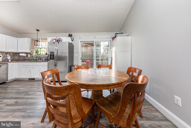 dining area with dark wood-type flooring, lofted ceiling, sink, and a textured ceiling