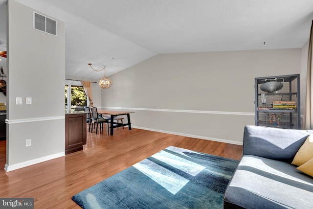 living room with lofted ceiling, hardwood / wood-style flooring, and an inviting chandelier