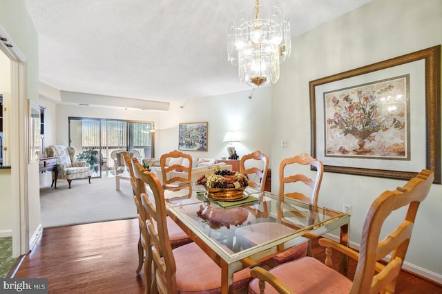 dining space featuring hardwood / wood-style floors, a textured ceiling, and a chandelier