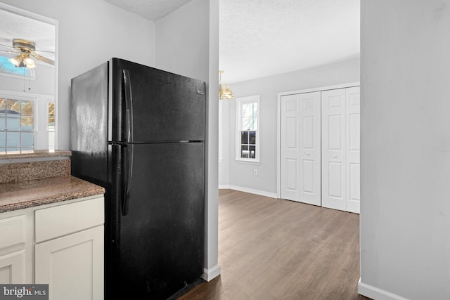 kitchen with ceiling fan, white cabinetry, a textured ceiling, black fridge, and dark hardwood / wood-style flooring