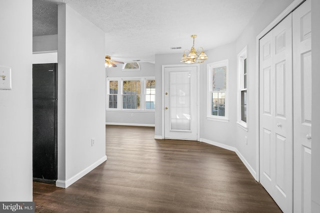 foyer featuring dark hardwood / wood-style floors, ceiling fan with notable chandelier, and a textured ceiling