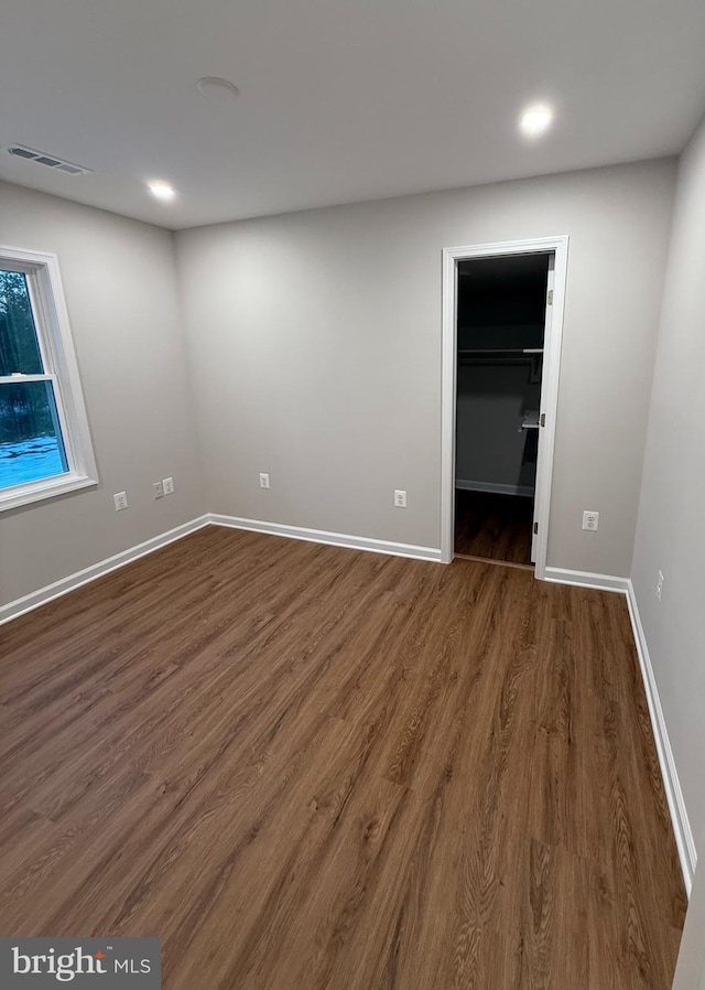 unfurnished bedroom with dark wood-type flooring, a closet, and a spacious closet