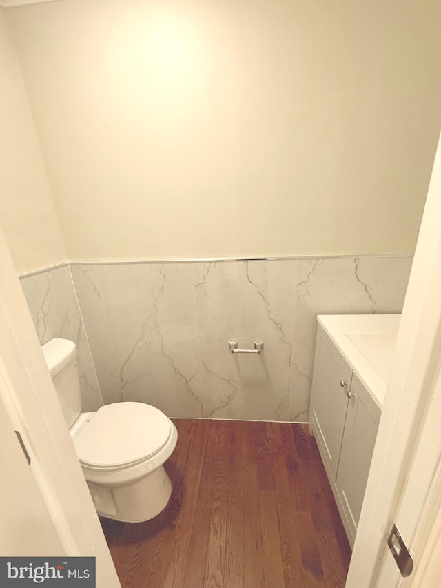 bathroom with toilet, vanity, tile walls, and hardwood / wood-style floors