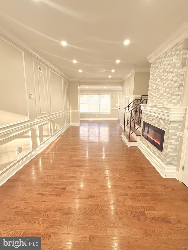 unfurnished living room with crown molding, a fireplace, and wood-type flooring