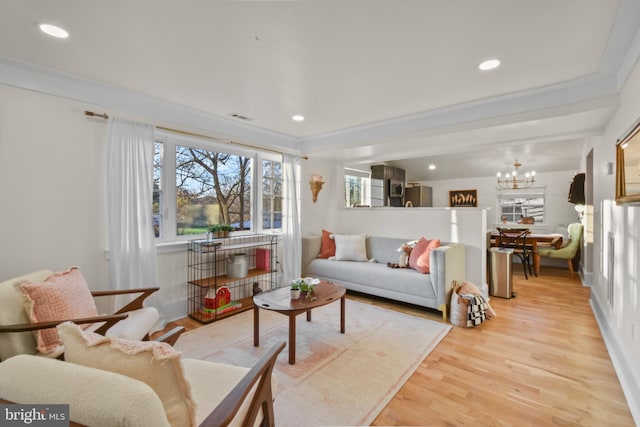 living room featuring crown molding, a chandelier, and light wood-type flooring