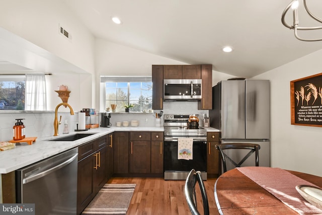 kitchen featuring lofted ceiling, appliances with stainless steel finishes, sink, and backsplash