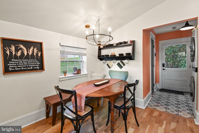 dining area featuring vaulted ceiling, a chandelier, and light wood-type flooring