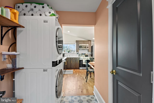 clothes washing area with light wood-type flooring and stacked washer / dryer