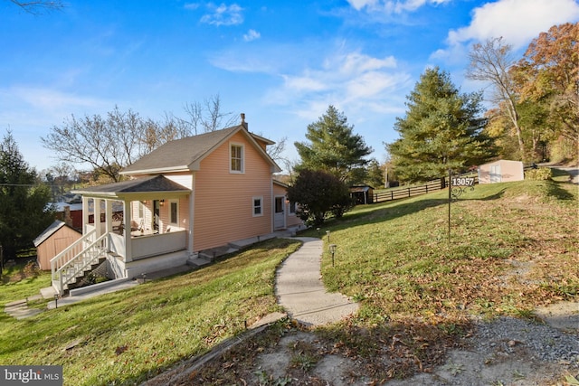 view of side of home with a porch, a shed, and a lawn